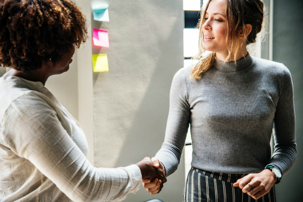 Two sharply dressed women shaking hands after meeting each other